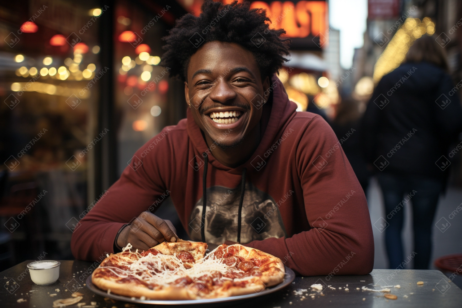 Young African American man eats a pizza outdoor. Fast food concept.