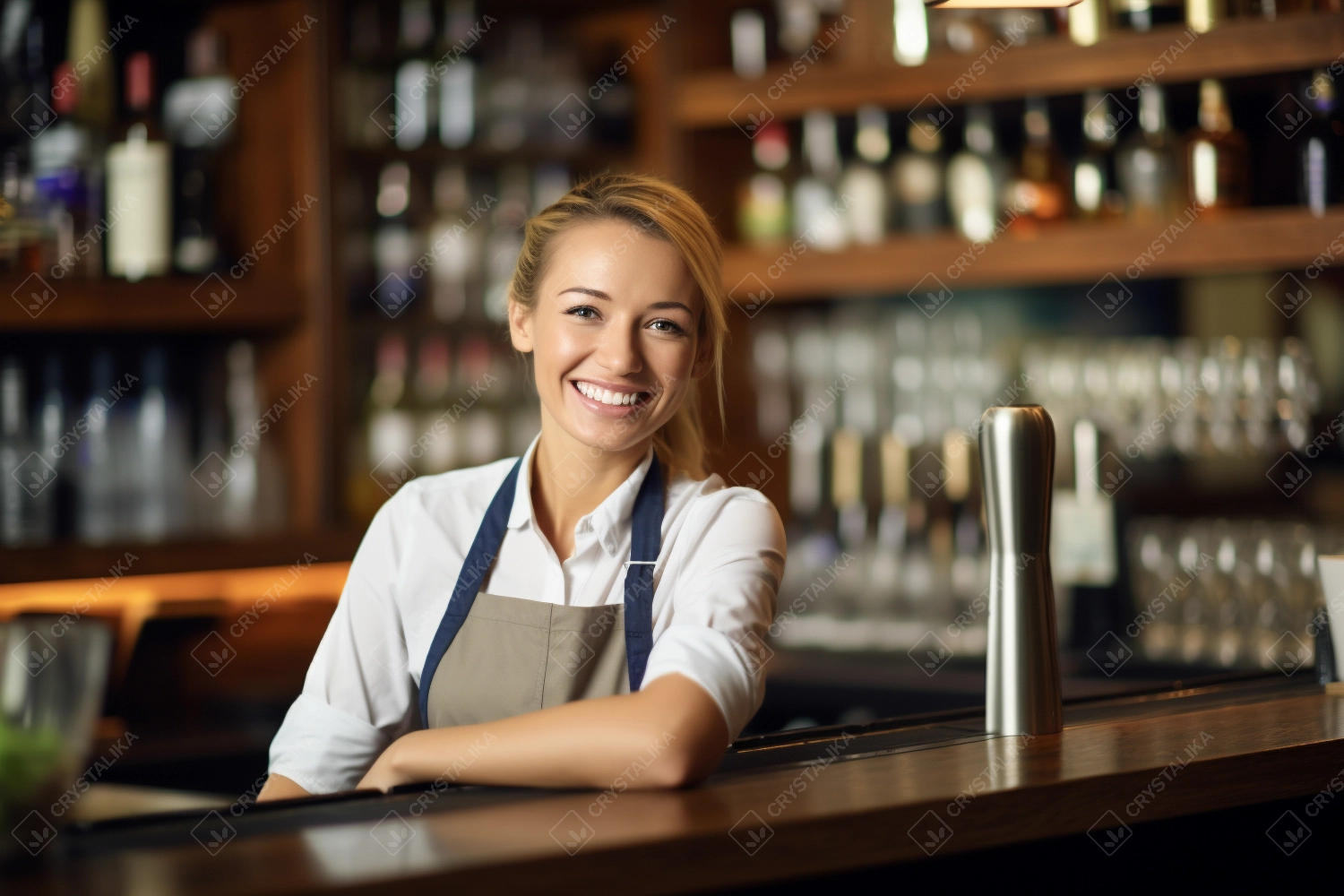 Portrait of happy young woman who works as a bartender at bar. Beautiful waitress or small business owner barista bartender standing in apron at the bar counter in restaurant.