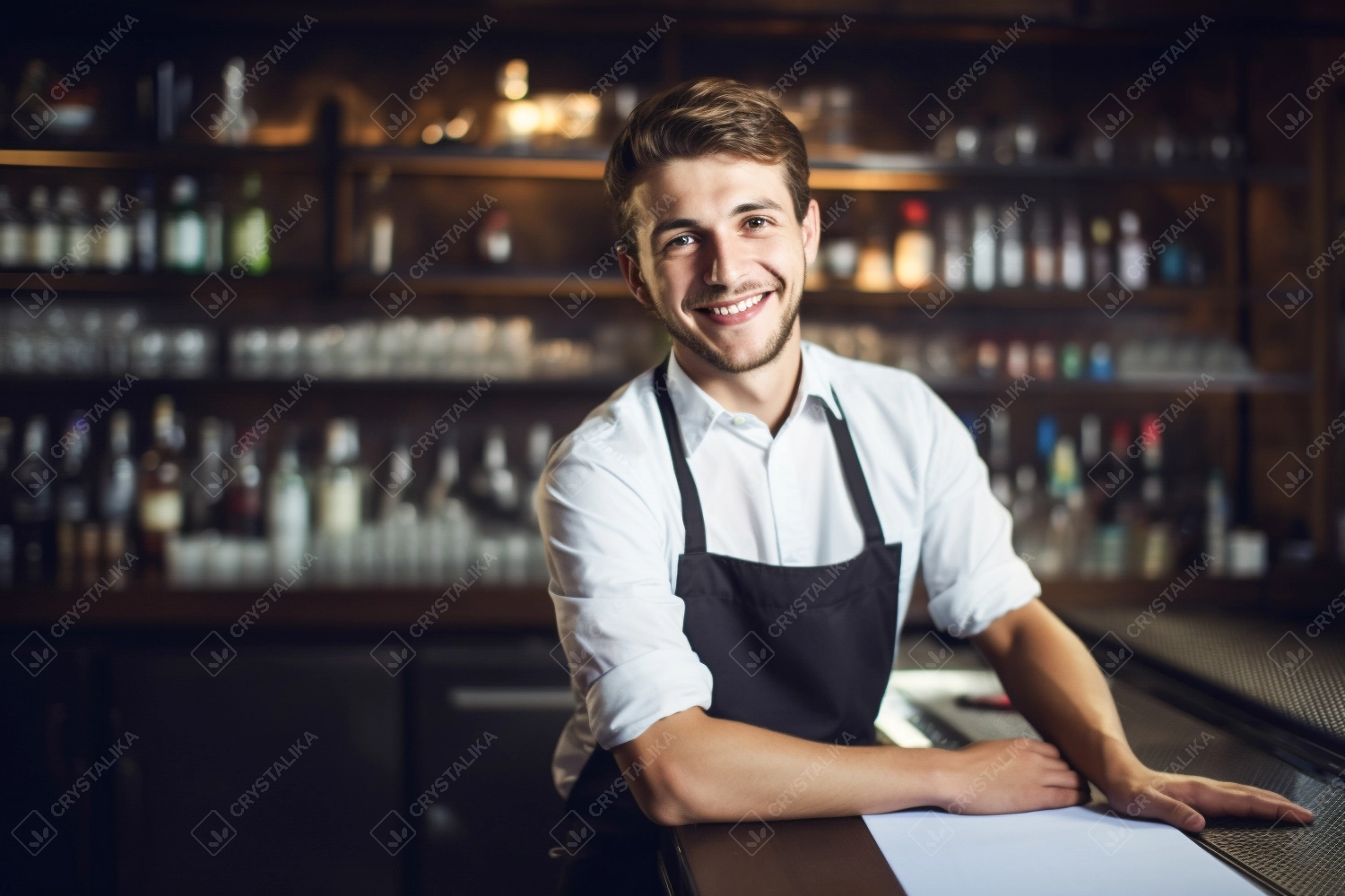 Portrait of happy young man who works as a bartender at bar. Beautiful waiter or small business owner barista bartender standing at the bar counter in restaurant.